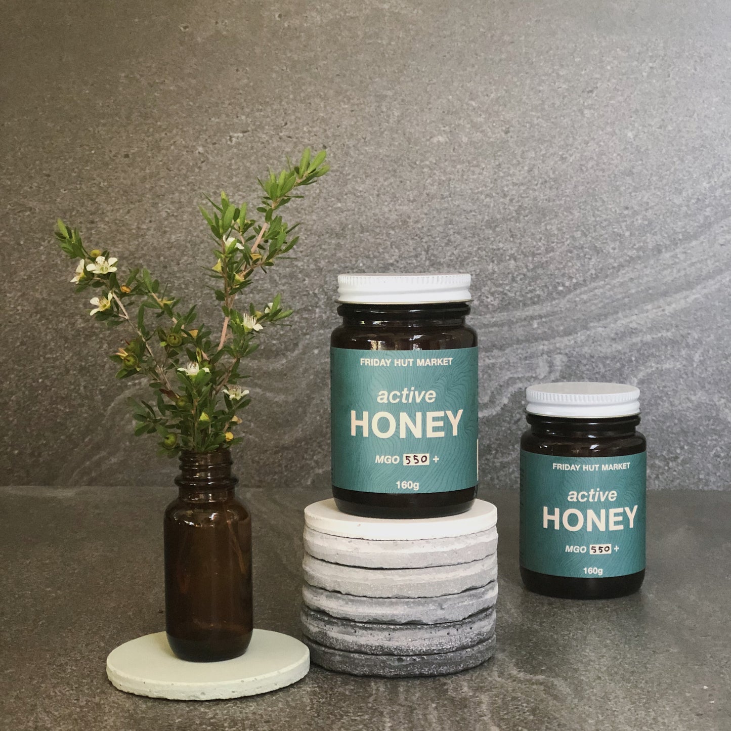 Jars of Friday Hut Market MGO 550+ Active Jellybush Honey, with picked Leptospermum Jellybush plant flowers. Australia's Manuka