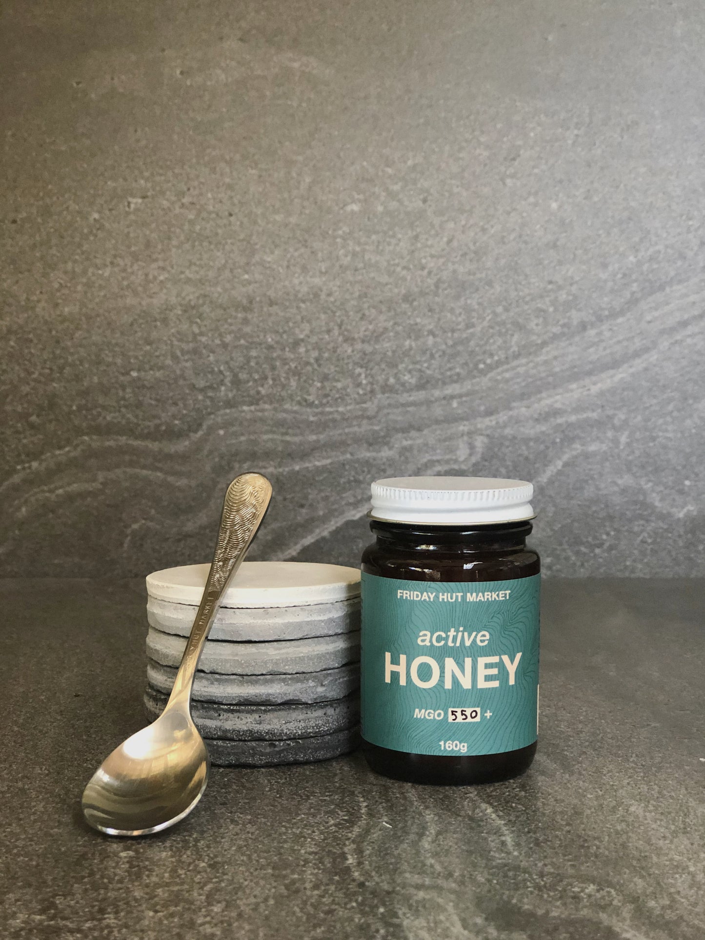 A Jar of Friday Hut Market MGO 550+ Active Jellybush Honey with a teaspoon. Australia's Manuka