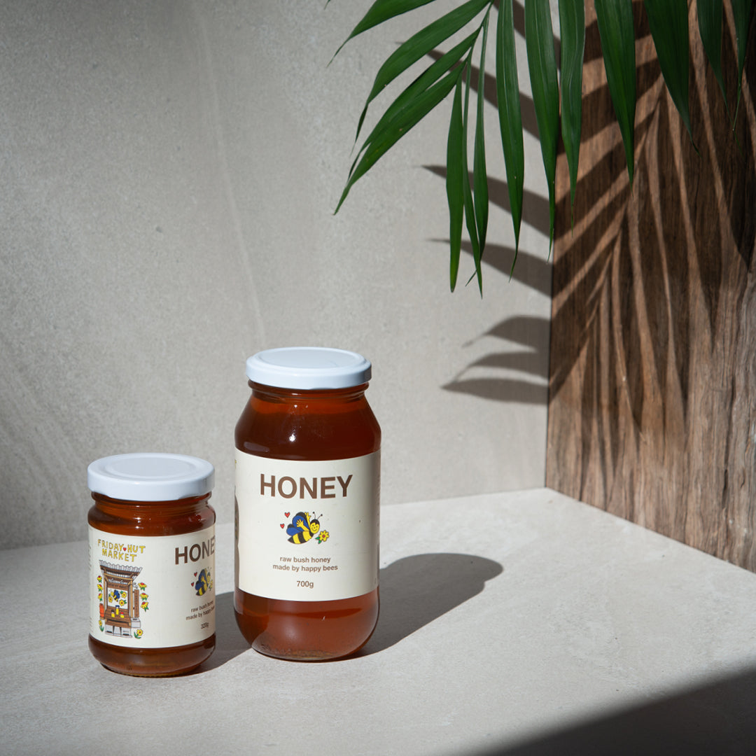 320g and 700g jars of Friday Hut Market Raw Bush Honey sits with a leaf in the background.