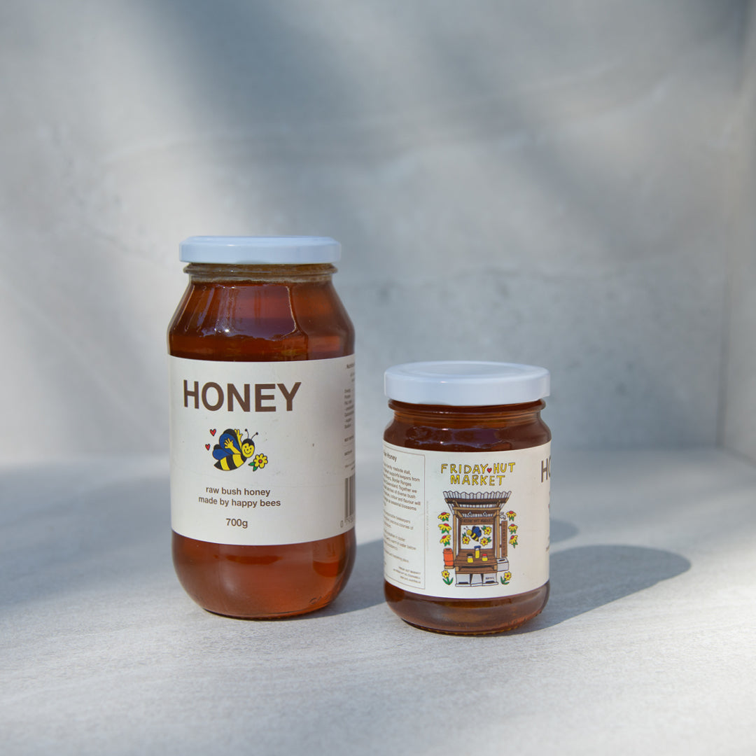 320g and 700g jars of Friday Hut Market Raw Bush Honey are standing next to each other with a tile background.