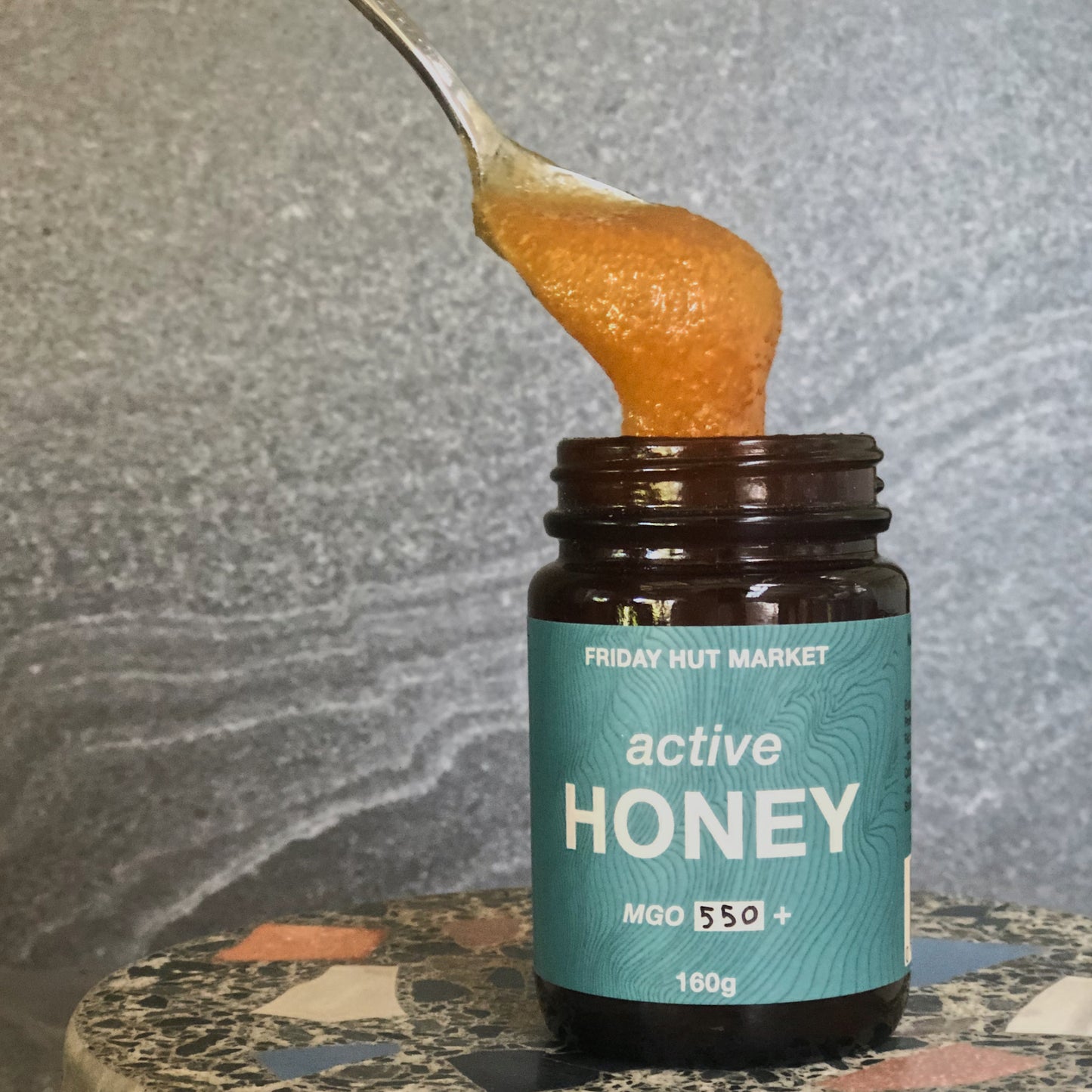 A spoon of thick golden Friday Hut Market MGO 550+ Active Jellybush Honey, Australia's Manuka